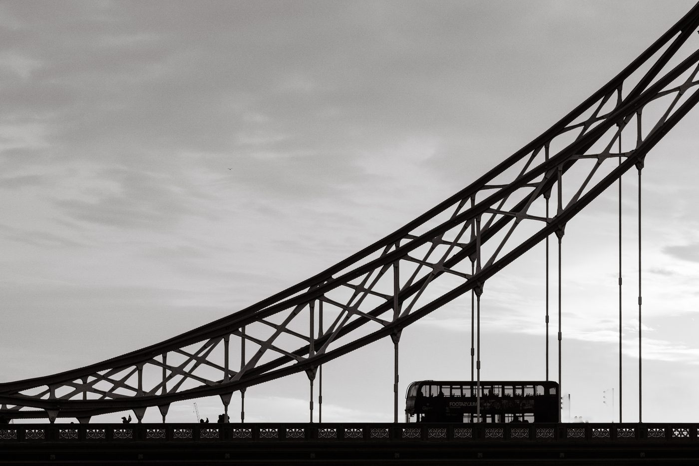Tower Bridge span backlit, a double-decker bus in silhouette, black and white