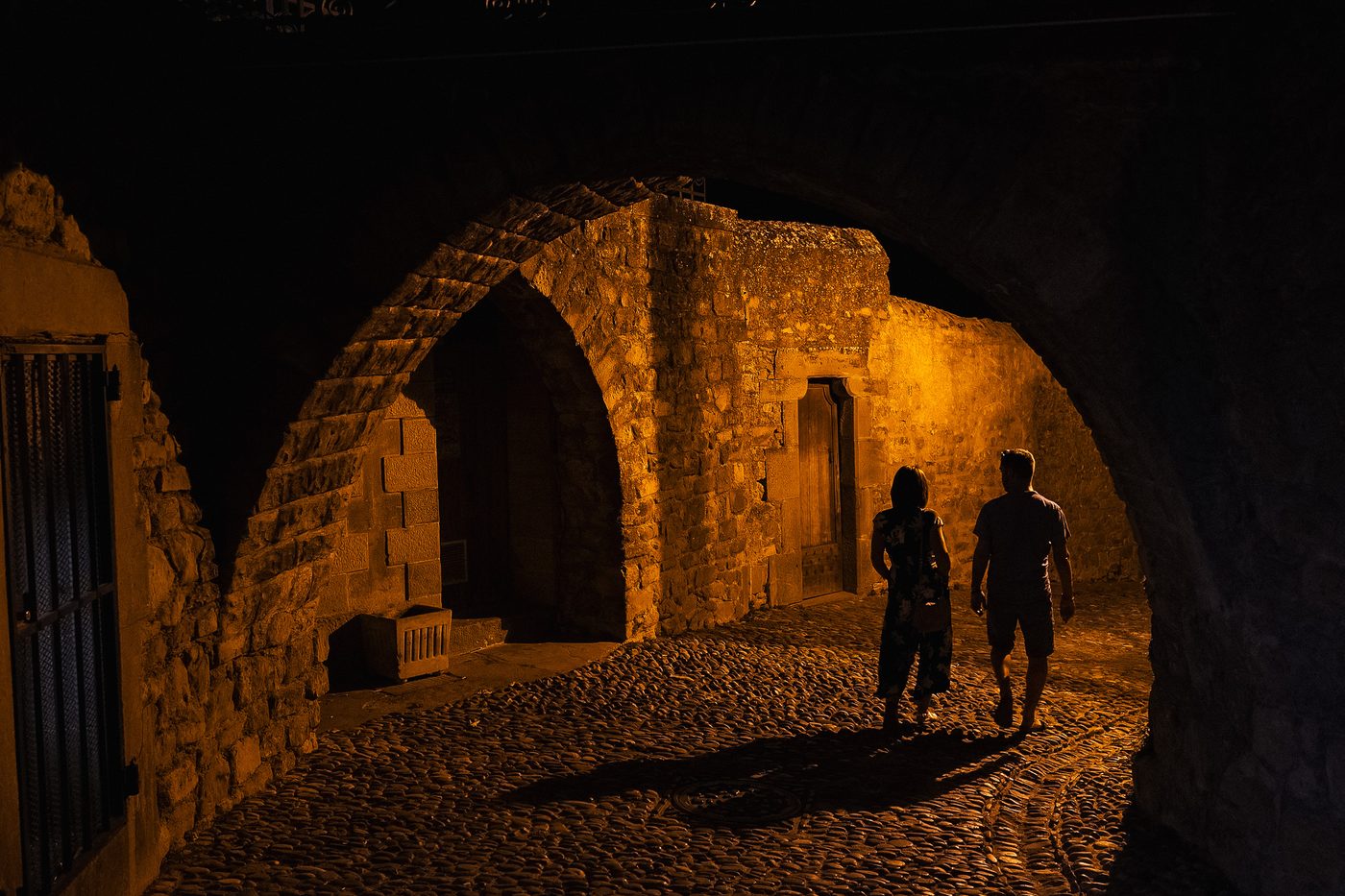Deux silhouettes sous une arche éclairée, Cité de Carcassonne la nuit
